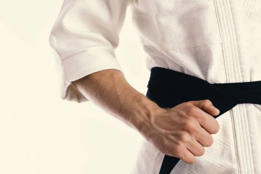 Adam siyah kuşaklı beyaz kimonoyla poz veriyor..