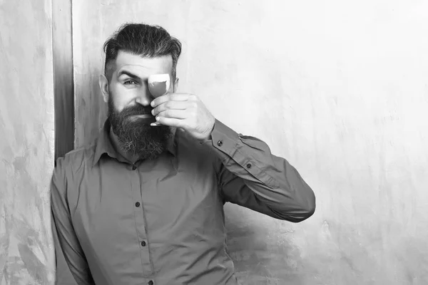 Homem barbudo, barba comprida. Brutal caucasiano sério hipster com bigode em camisa marrom segurando tiro vermelho alcoólico sobre fundo textura dourada . — Fotografia de Stock