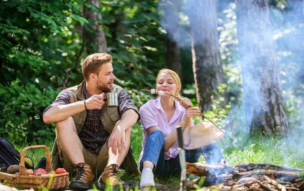 Couple take break to eat nature background. Couple in love camping forest hike. Food for hike and camping. Couple sit near bonfire eat snacks and drink. Hike snacks and beverages. Hike picnic