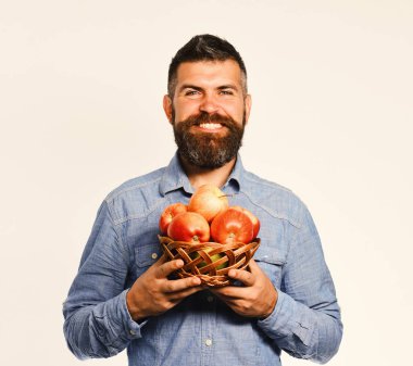 Sakallı adam elinde meyve dolu hasır kasesi tutuyor.