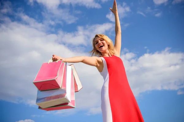 Woman red dress carries bunch shopping bags blue sky background. Feel free buy everything you want. Finally bought favorite brands. Tips shop summer sales successfully. Girl satisfied with shopping