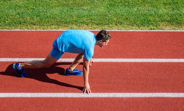 Athlete runner prepare to race at stadium. How to start running. Running tips for beginners. Man athlete stand low start position at stadium path. Beginning of new lifestyle habit. Runner ready to go