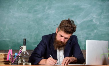 Rapor yazma. Öğretmen ile kalem evrak ile meşgul yazma adam sakallı. Öğretmenlerin günlük rutin evrak ve rapor yazma. Öğretmen resmi ceket oturup tablo sınıf kara tahta arka plan