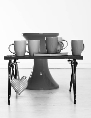 Pembe Kalp beyaz zemin üzerine kırmızı sandalye ve renkli bardak ve bir kitap ile siyah ahşap tepsi ter.