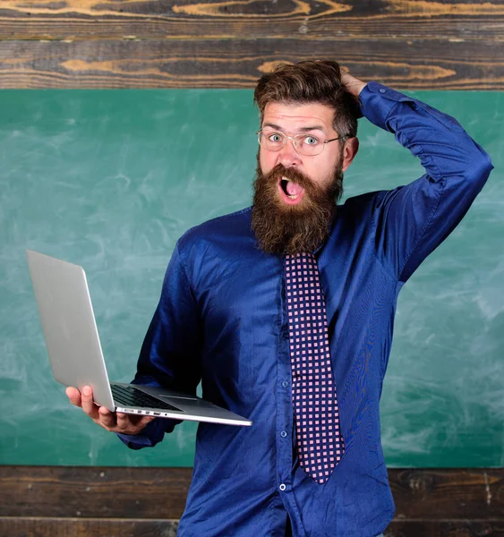 Modern technology blows his mind. Teacher bearded man with modern laptop chalkboard background. Modern educational program. Hipster teacher surprised with laptop goes crazy about educational program