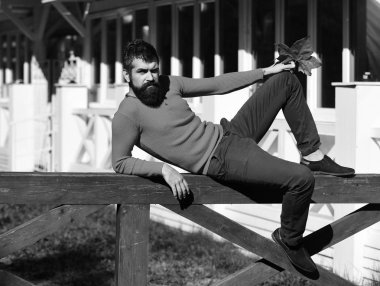 Sakallı adam tırabzanda yatıyor. Kendine güvenen bir adam.