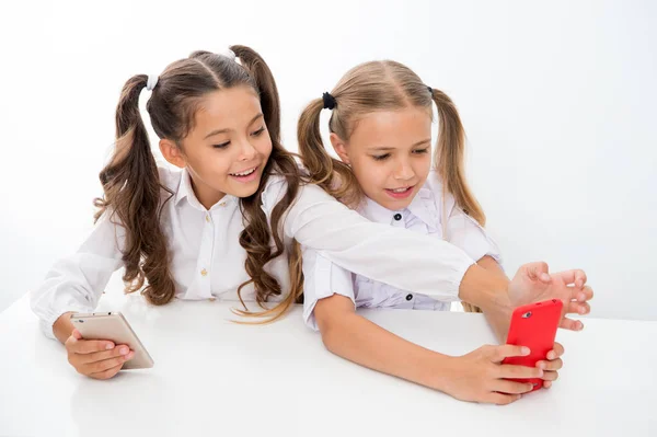 Schulpause für glückliche kleine Mädchen mit Smartphones. Kleine Mädchen, die in der Schulpause Smartphones benutzen, haben Spaß. — Stockfoto