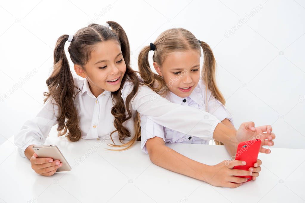 school break for happy little girls using smartphones. little girls using smartphones on school break having fun.