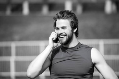 Mutlu bir adam konuşmak üstünde hareket eden telefon güneşli açık, iletişim. Sakallı adam smartphone ile modern hayatın gülümse. Sporcu mavi spor tshirt, moda içinde. Spor moda ve sağlıklı yaşam tarzı