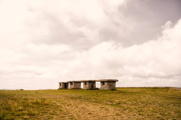 Маленькие каменные пустующие домики на зеленой траве и облачном небе — стоковое фото