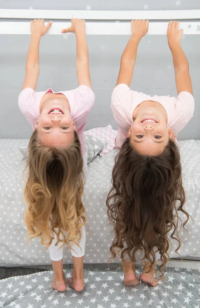Little girls with long blond hair hang upside down. Hair salon for kids — Stock Photo, Image
