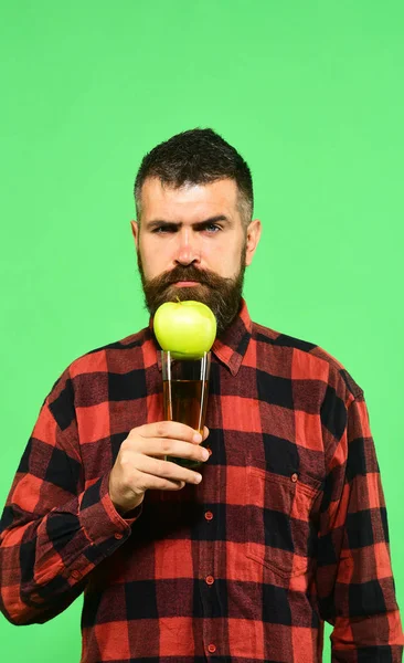 Guy shows harvest product. Man holds glass of apple juice — Stock Photo, Image