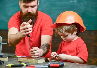 Çocuk, Çocuk koruyucu kask babamla tornavida kullanmayı öğrenme içinde meşgul. Tamirci ve atölye kavramı. Baba, sakallı aracı tornavida kullanmak için küçük oğlu öğretim üst