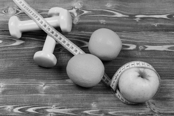 Sport training concept, dumbbells weight with measuring tape, orange, apple — Stock Photo, Image