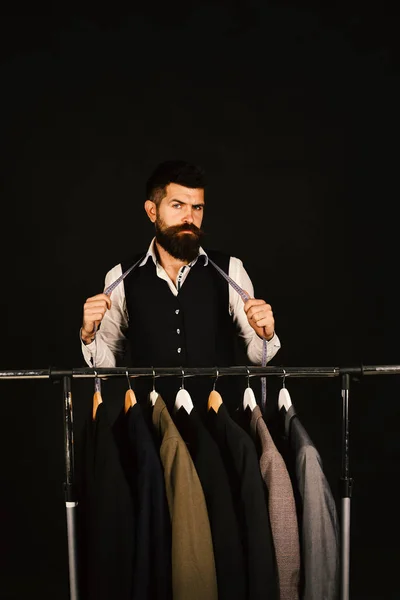 Man with beard in vest by clothes rack. — Stock Photo, Image