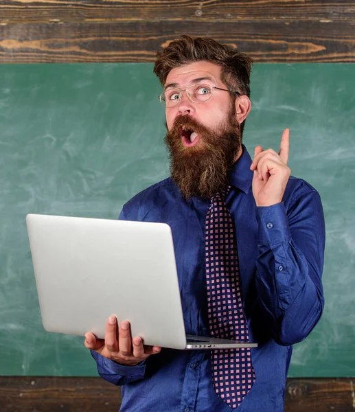 Iskolában innovációs. Csípő tanár viselnek szemüveget, és nyakkendő tart laptop internet szörfözés. Tanár szakállas ember modern laptop szörfözés internet Palatábla háttérrel. Távolság oktatási koncepció — Stock Fotó