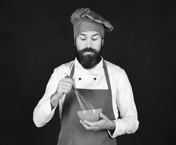 Homme ou hipster avec barbe tient ustensiles de cuisine sur fond noir — Photo