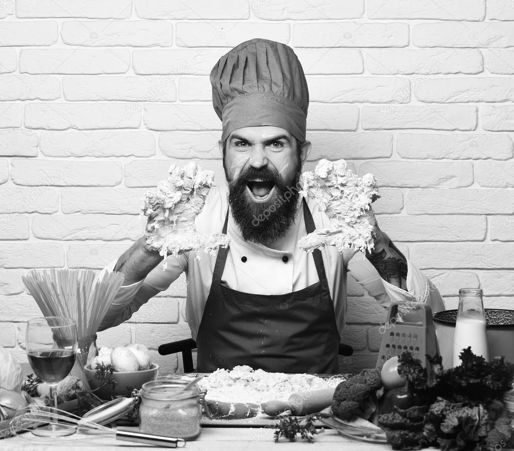 Chef kneads dough. Man with beard and hands in dough