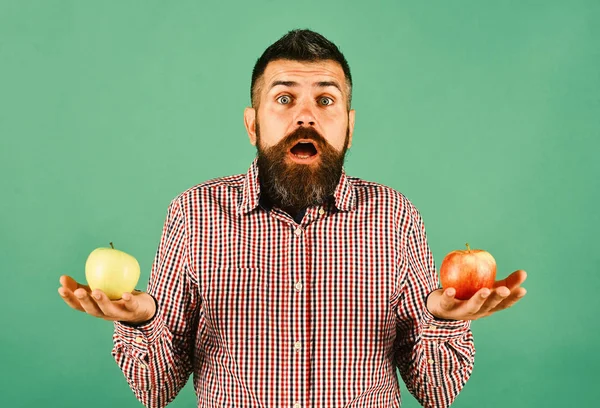 A meglepett arcú gazda két friss gyümölcs között dönt.. — Stock Fotó