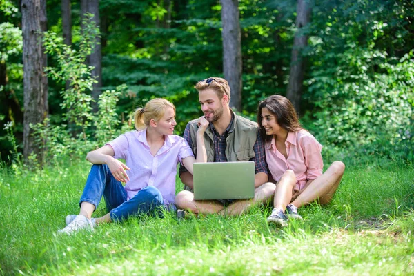 Les jeunes de l'entreprise passent leurs loisirs à l'extérieur avec un ordinateur portable. Amis travaillant avec un ordinateur portable à Green Meadow. Les technologies modernes offrent la possibilité de travailler dans toutes les conditions environnementales. Possibilité de freelance — Photo