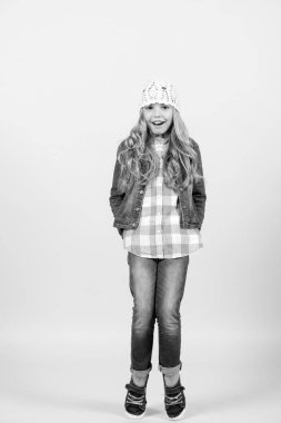 Uzun sarı saçlı, gülümseyen ve parmak uçlarında duran çocuk modeli.