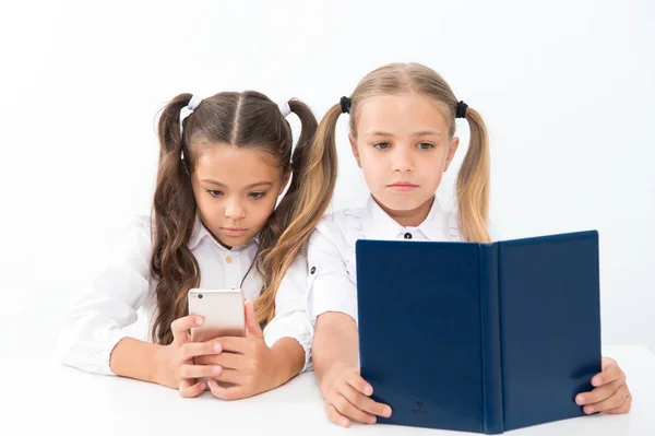 Lesekonzept. Sich informieren. Kleine Mädchen lesen Papierbuch und E-Book im Smartphone. Die richtige Wahl — Stockfoto