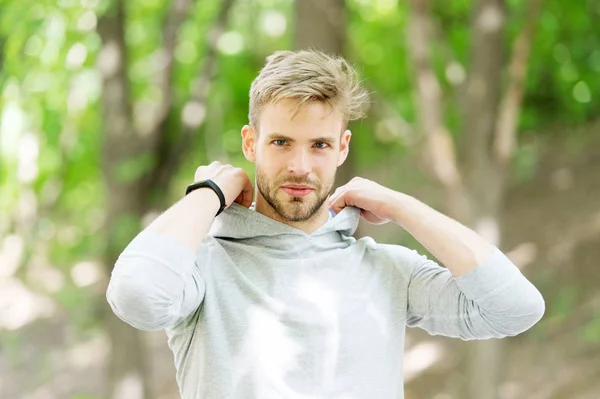 Guy bearded attractive casual put hood on . Man with bristle smiling face nature background defocused. Man unshaven guy looks handsome casual hooded. Comfortable clothing. Feeling comfortable