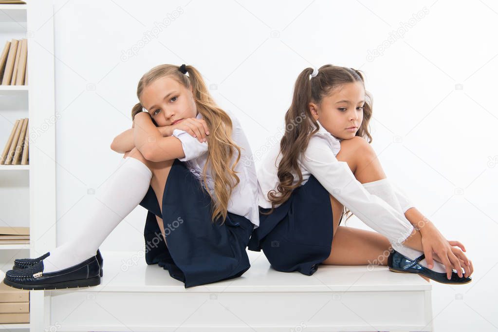 insult. insult of two small girls children or sisters at school. small girls in school uniform.