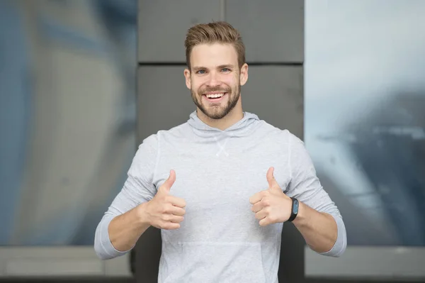Approve or recommend concept. Man with brilliant smile unshaven face shows thumbs up gesture urban background. Guy happy emotional approve expression. Man happy cheerful face support you or recommend