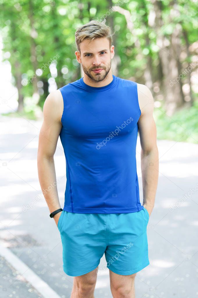 Enjoy wellbeing and healthy body. Man sporty outfit looks confident outdoors nature background. Guy bearded muscular body proud of his shape. Sportsman enjoy his muscular body proud of himself