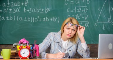 O senin rapor ya da bilgi şüphe vardır. Öğretmen kadın tablo sınıf kara tahta arka plan otur. Öğretmen, bilgi ve becerileri hakkında şüpheli. Öğretmen kuşkuyla gözlük dışarı bakmak