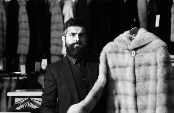 El hombre con barba sostiene el abrigo de piel. Concepto de ropa de lujo . — Foto de Stock