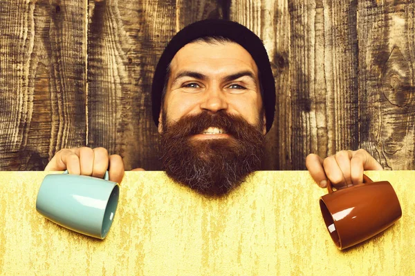 Barbudo brutal hipster caucásico con hoja de papel y tazas —  Fotos de Stock