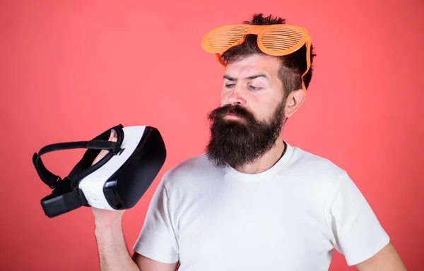 Alternative Realität. Mann bärtiger Hipster mit Virtual-Reality-Headset und Sonnenbrille vor rotem Hintergrund. Welche Brille man wählen kann, ist offen oder virtuell. Der Mensch entscheidet, was real oder virtuell ist — Stockfoto