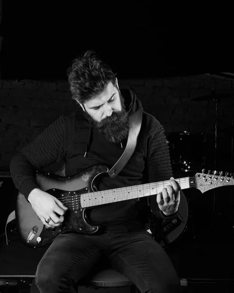 Man with busy face in black clothes holds guitar, play — Stock Photo, Image