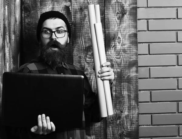 Bearded brutal caucasian hipster holding laptop and craft paper