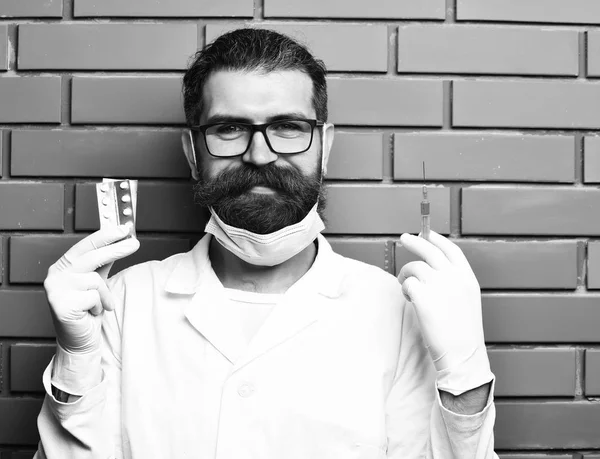 Bearded brutal caucasian doctor or postgraduate student holding pills — Stock Photo, Image