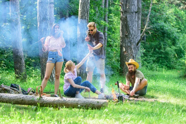 Sommerpicknick beitreten. Treffen für ein großes Picknick. Gesellschaft, die sich beim Würstchenbraten am Spieß vergnügt. Freunde treffen sich am Lagerfeuer, um abzuhängen und Bratwürste zuzubereiten. — Stockfoto