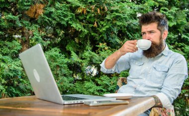 Adam kahve rahatlatıcı Teras dalları arka plan içer. Aroma kapuçino. Hoş bir an. Sakallı adam hipster yapmak kahve içmek için duraklatmak ve dizüstü bilgisayar ile oturup süre rahatla. Hayattan zevk için zaman ayırın