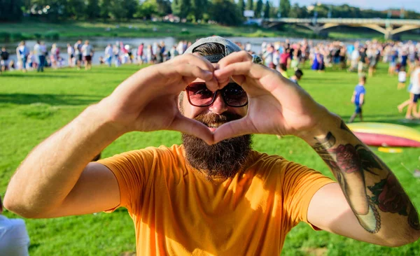 Muž vousatý před davem lidí show srdce gesto u řeky pozadí. Veselá ventilátor love symbol speciálního tahu. Bokovky šťastné Oslavte festival událost fest piknik. Mám rád letní dovolená festival — Stock fotografie