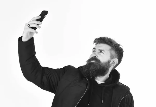Чоловік зі спокійним обличчям в теплому одязі і тримає телефон — стокове фото