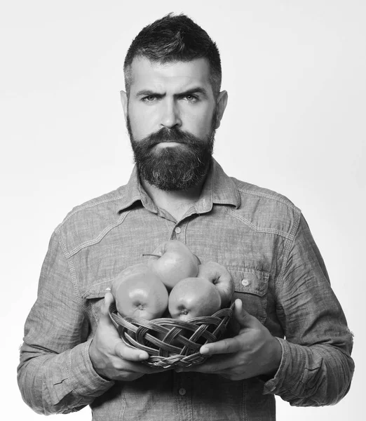 Hombre con barba sostiene cuenco de mimbre con fruta —  Fotos de Stock