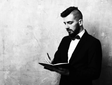 Özenli görünümlü sakallı ofis müdürü deftere planlar yazar.