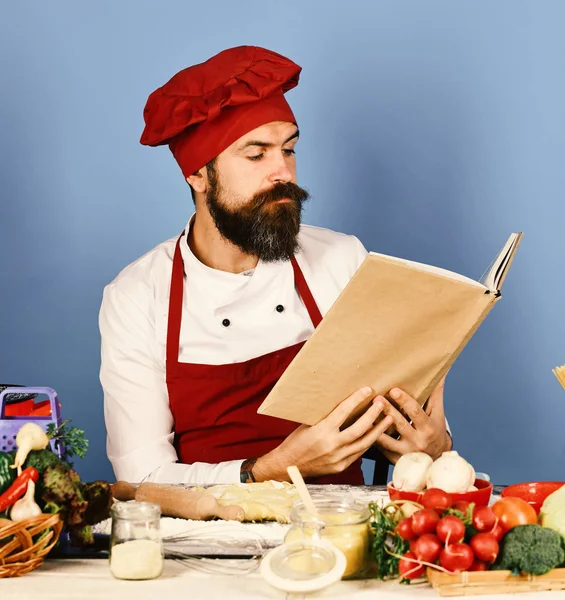 Professionelles Küchenkonzept. Mann mit Bart hält Rezeptbuch in Händen — Stockfoto