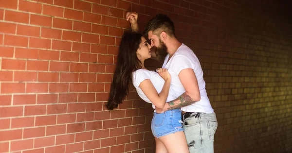 Girl and hipster full of desire cuddling. Couple in love full of desire brick wall background. No rules for them. Couple find place to be alone. Couple enjoy intimacy without witnesses public place