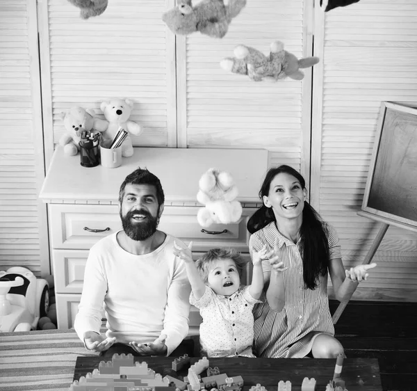 Mutlu yüzlü ebeveynler ve oğulları yumuşak oyuncaklarla oynuyorlar.