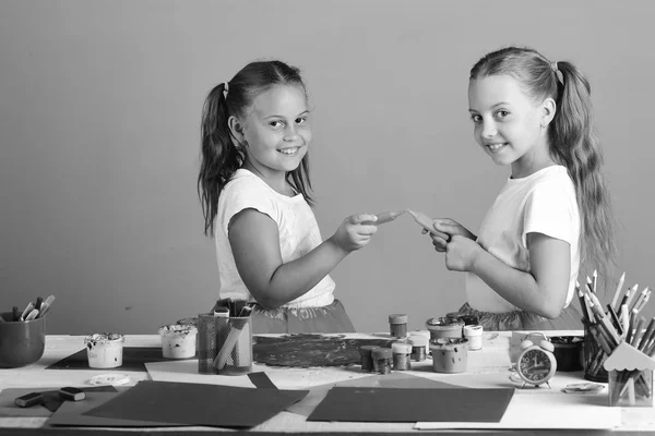 Niños por mesa blanca con pinturas, papel y papelería —  Fotos de Stock