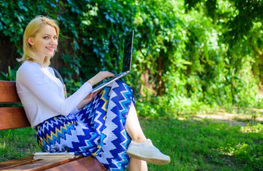 Serbest zaman Park İnternet'te sörf. Doğada net sörf. Kadın dizüstü bilgisayar ile açık, yeşil doğa arka çalışır. Bayan freelancer enterne dalga köpüğü ya da parkta çalışma. Kız oturup Not defteri ile tezgah