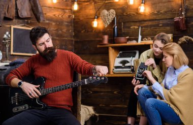 Rock müzisyeni trendy sakal ve bıyık gitar çalmak. Sakallı adam ayarlama müzik aleti. Anne ve kızı Baba, müzik, eğlence etkinlik kavramı birçok parçalardan oluşan eski video kamera ayarlama