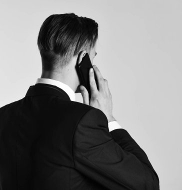 Gri arka planda cep telefonuyla konuşan adam..